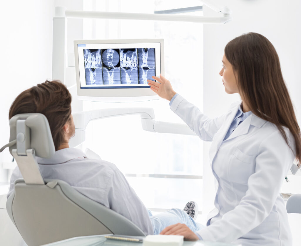 Restorative Dentist 1 Restorative dentist explaining her patient in chair x-ray results to help illustrate cosmetic dentistry vs restorative dentistry