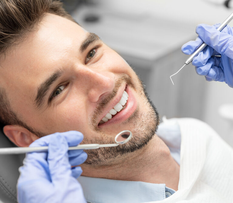 A man having their teeth examined to help illustrate cosmetic dentistry procedures.
