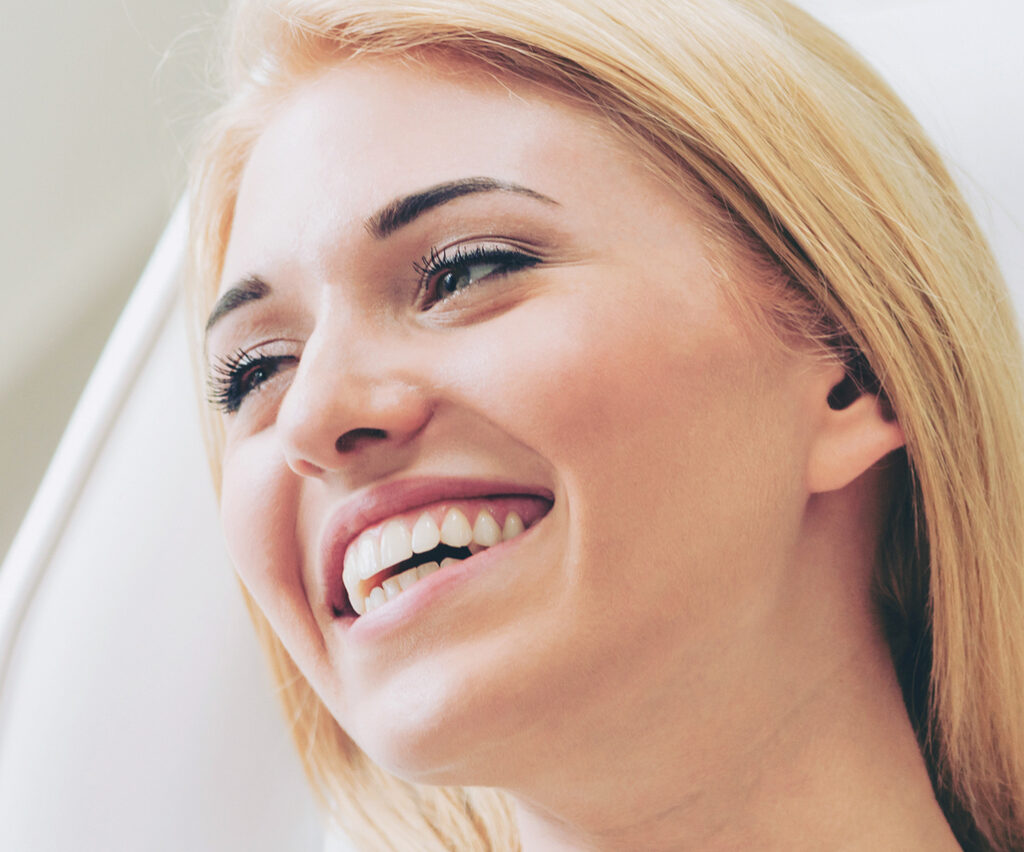 Happy woman patient sitting on dentist chair in dental clinic to illustrate benefits of cosmetic dentistry procedures