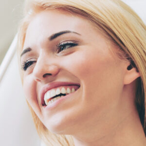 Happy woman patient sitting on dentist chair in dental clinic to illustrate benefits of cosmetic dentistry procedures
