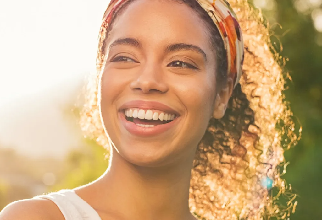 Smiling woman in a field to help illustrate five types of cosmetic dentistry procedures