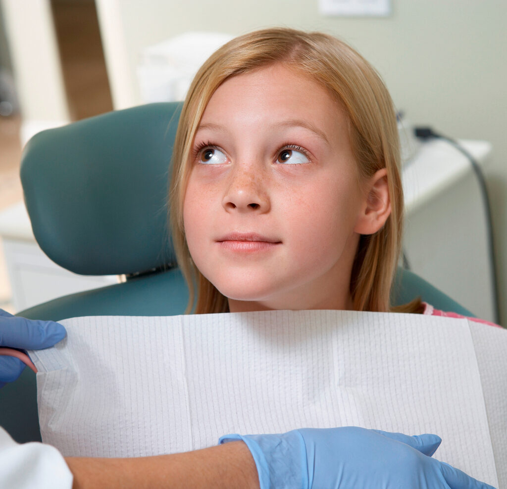 Girl Getting Dental Checkup and looking up to illustrate Is Pediatric Cosmetic Dentistry Safe?