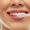 Closeup of smiling woman holding a tooth brush up to great teeth to help illustrate Common Restorative Dentistry Procedures