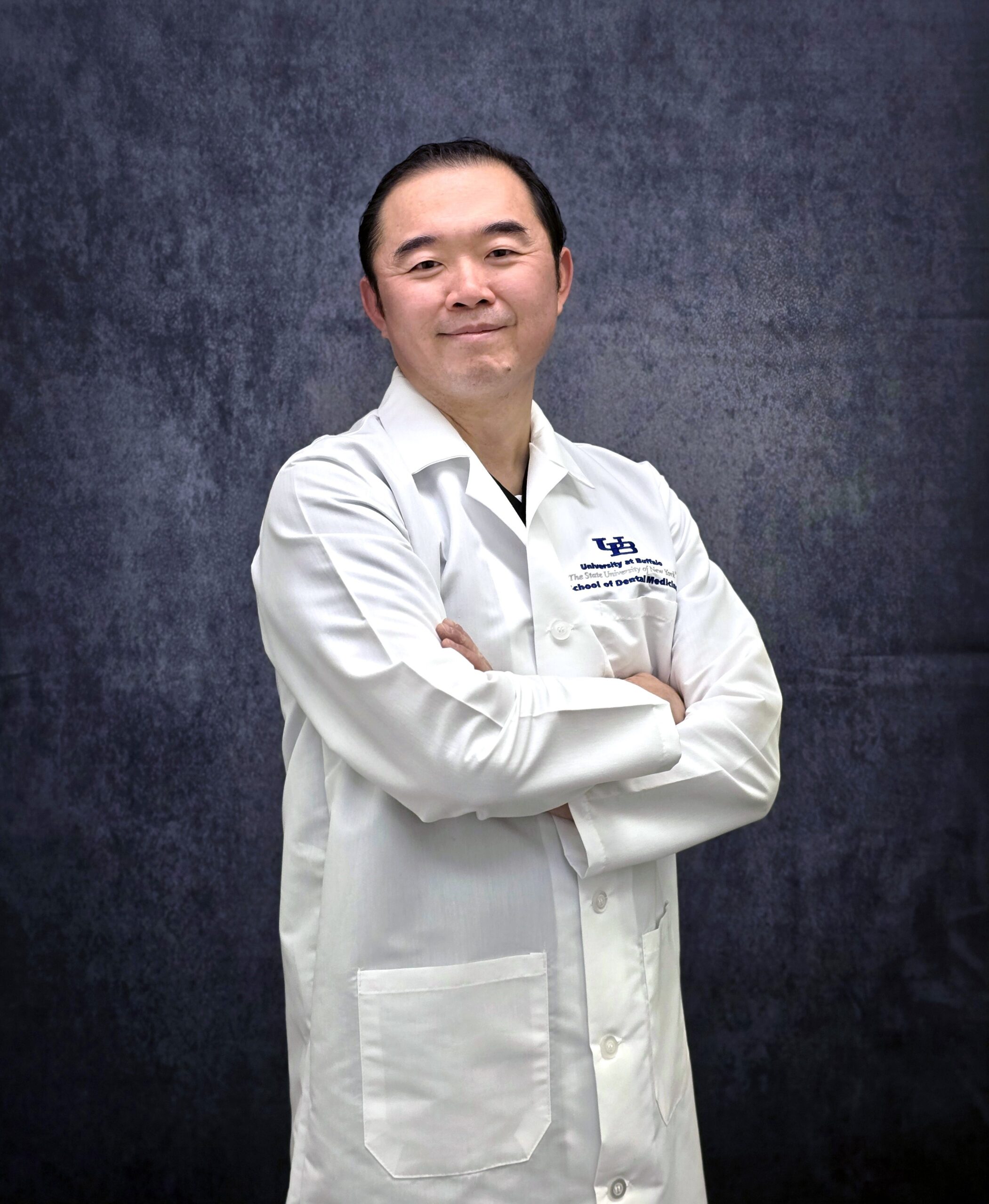 Asian Dentist in White Coat smiling with arms crossed