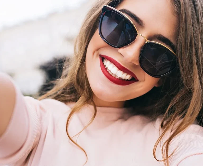 Cosmetic Dentist 9 A woman with sunglasses smiling.