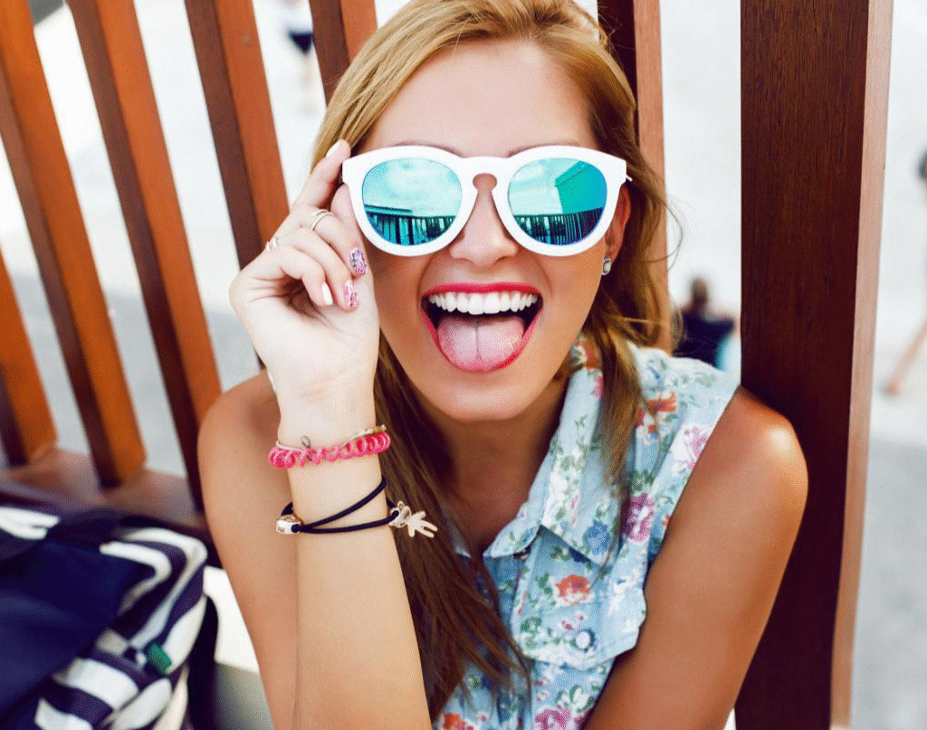Cosmetic Dentist 2 A woman with sunglasses smiling at the beach.