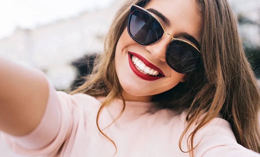 Cosmetic Dentist 9 A woman with sunglasses smiling.