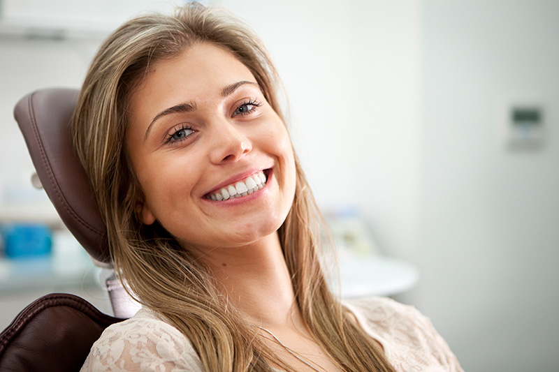 A person smiling while sitting in a dentist’s office