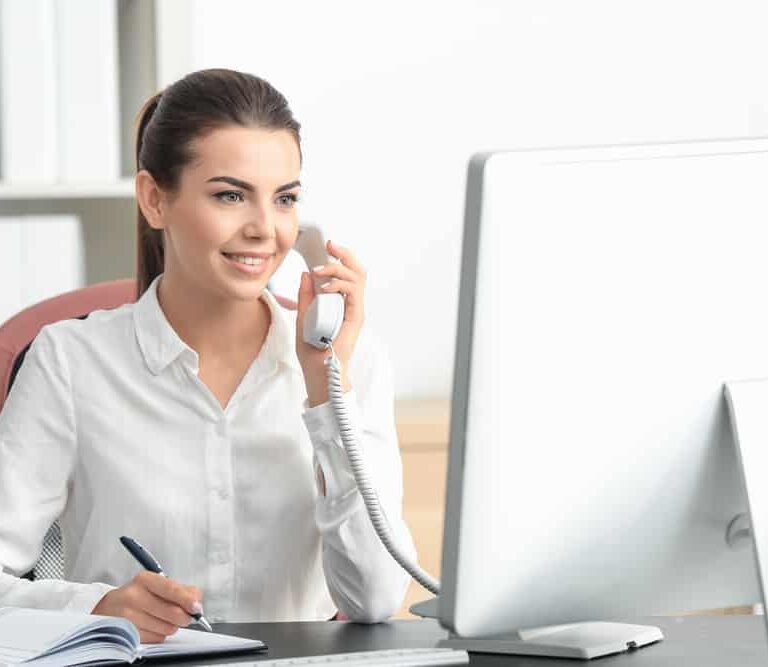 A person speaking on the phone while looking at a computer monitor