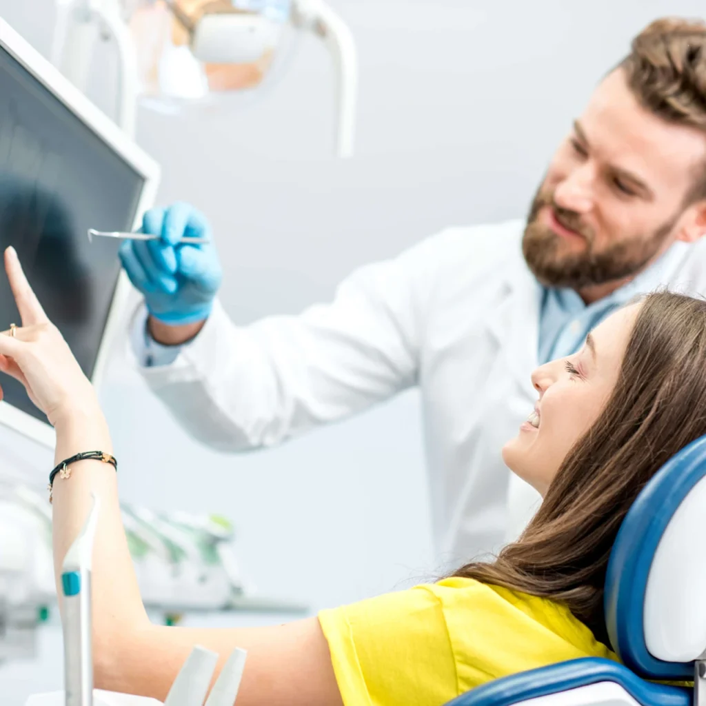 a dentist showing something on a screen to a patient