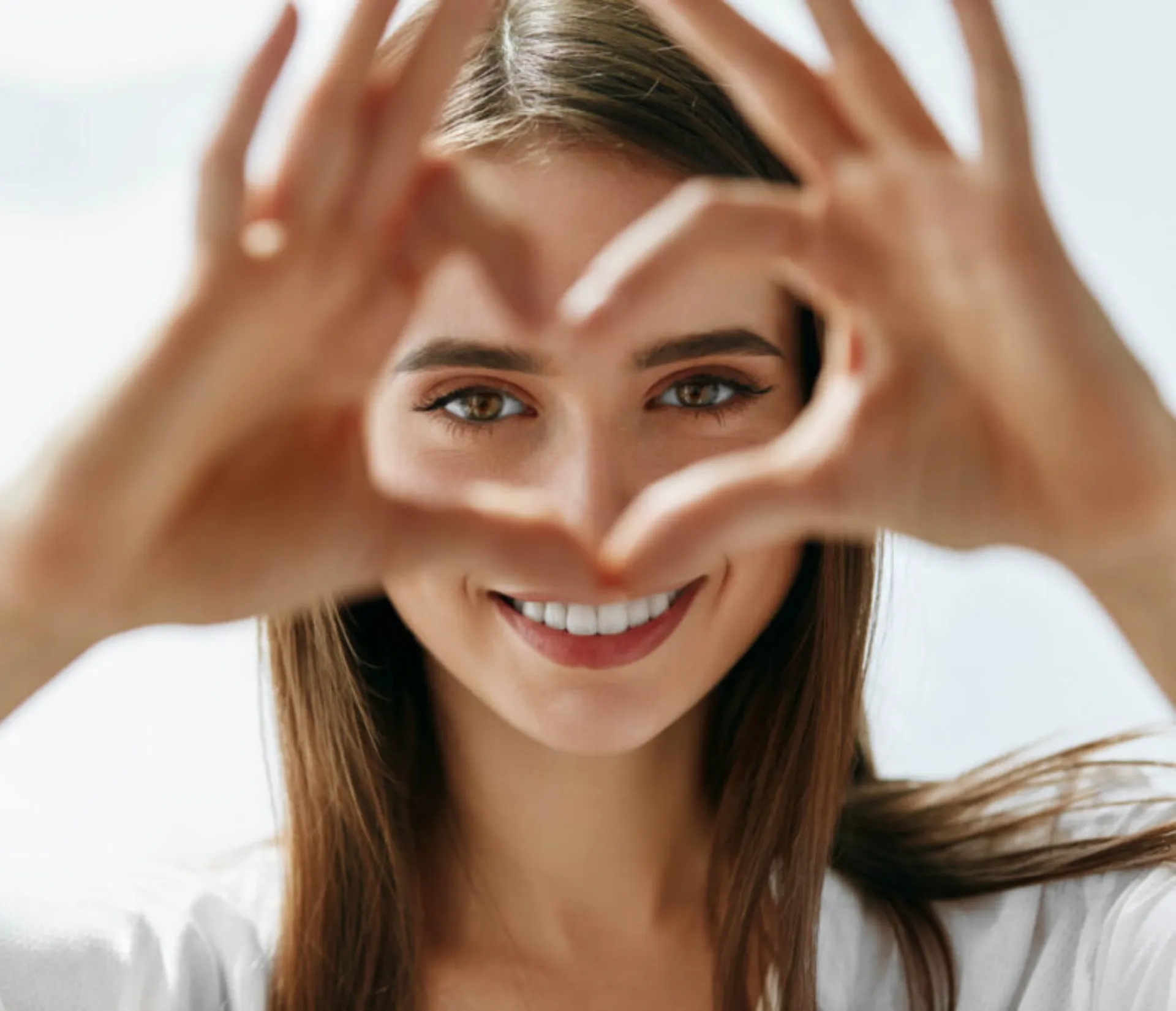 a woman smiling and creating a heart shape with her fingers