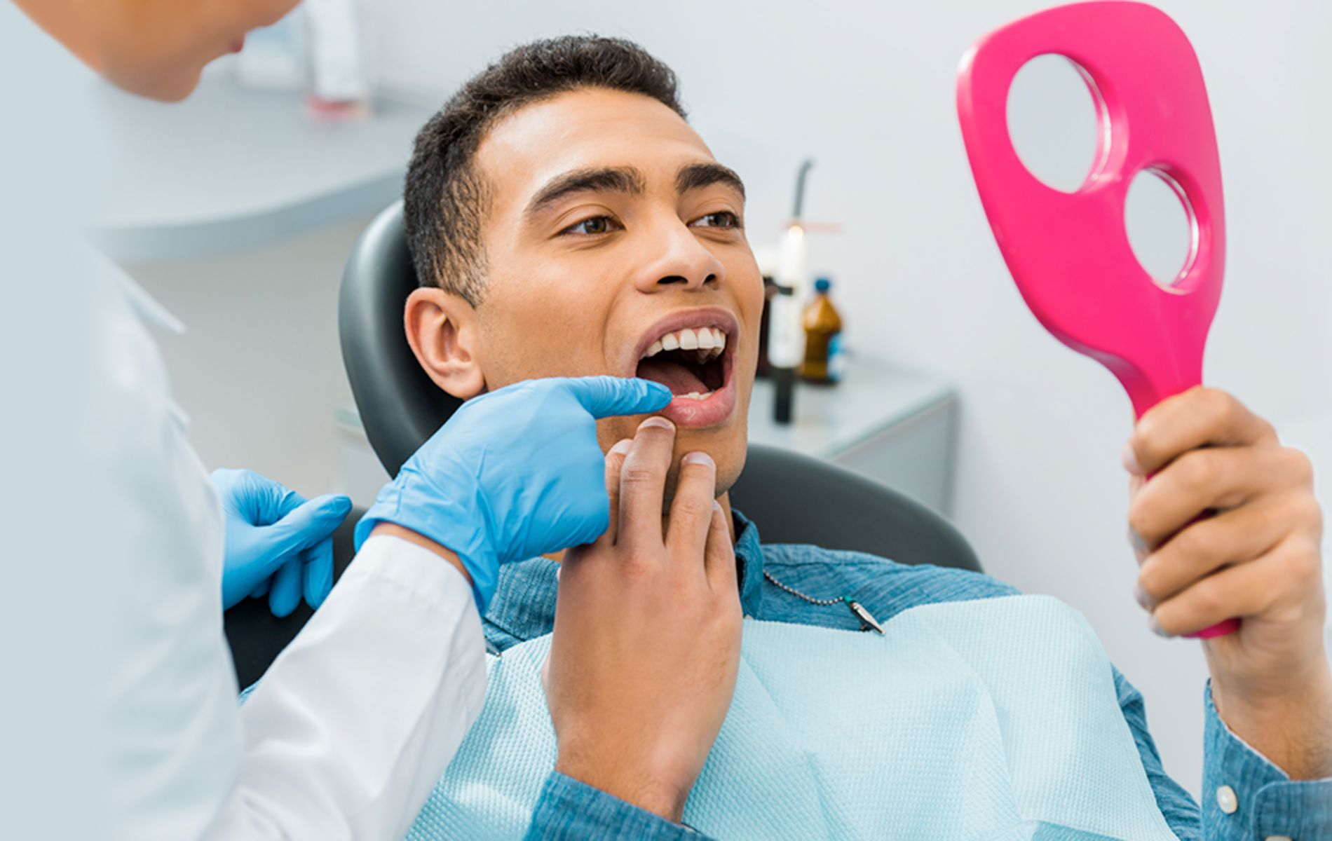 a gloved hand pointing to a patient’s tooth