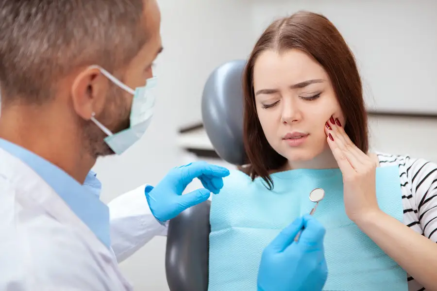 a patient at the dental office holding her cheek in pain